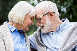 Elderly couple outside with foreheads pressed together smiling at each other